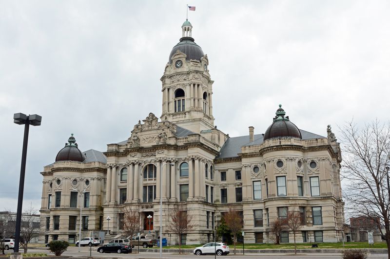 The Old Vanderburgh County Courthouse in downtown Evansville, a large pale limestone building with a central clock tower and domed corner towers